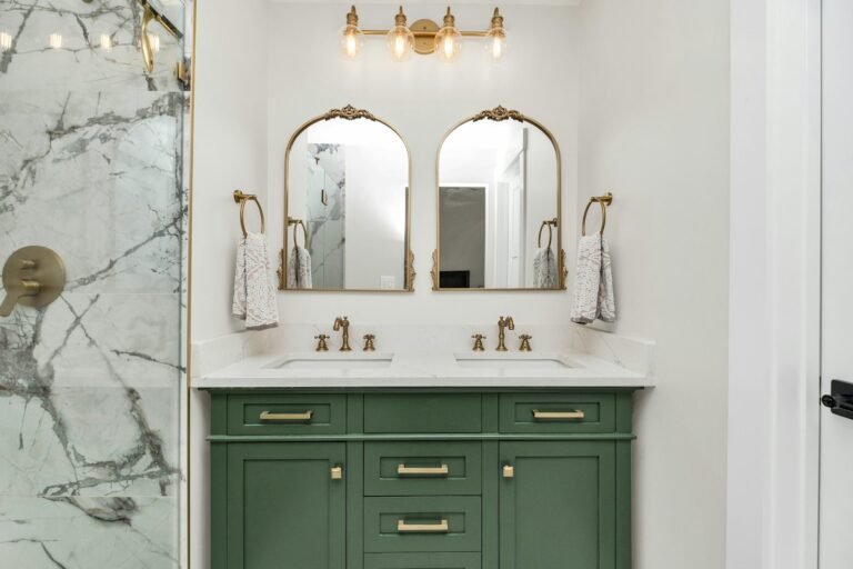 Bathroom vanity with mirror lit by wall sconces at eye level