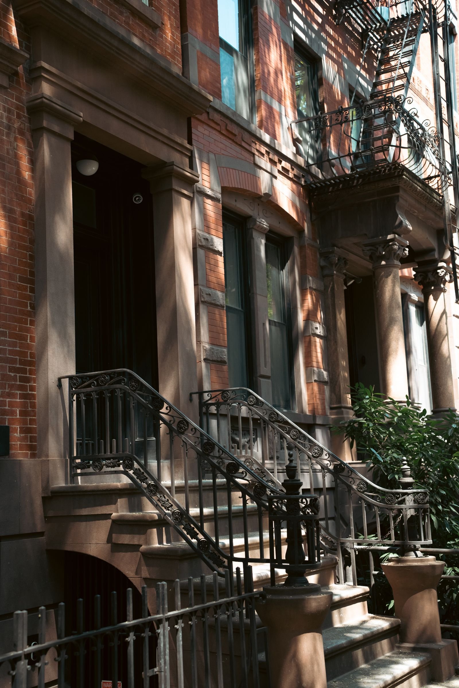 Brownstone building facade with ornate iron railings in afternoon light
