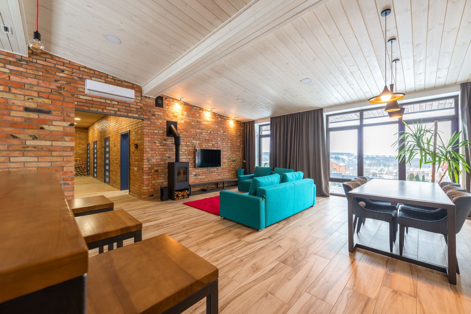 Living room with an exposed brick wall, teal sofa and tall windows