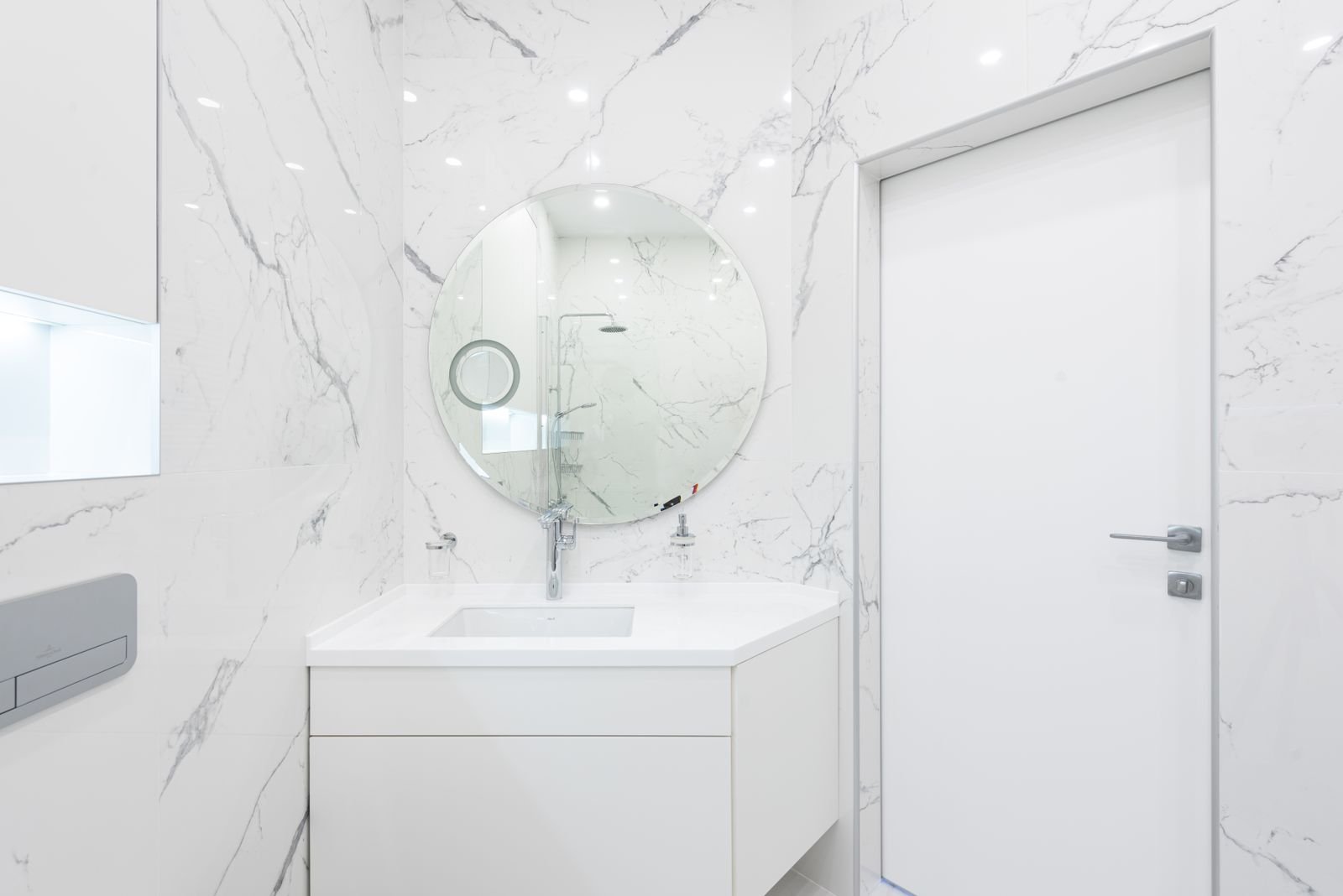 Small washroom with a cabinet vanity, sink and mirror beside the doorway